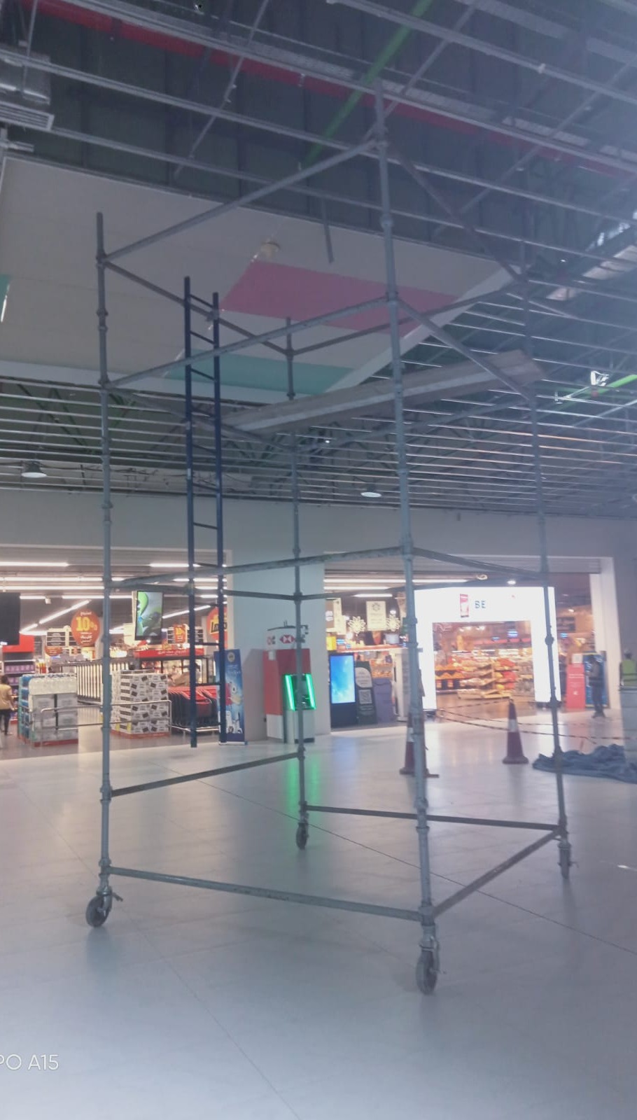 Mobile scaffolding erection beneath ceiling services in a commercial retail facility