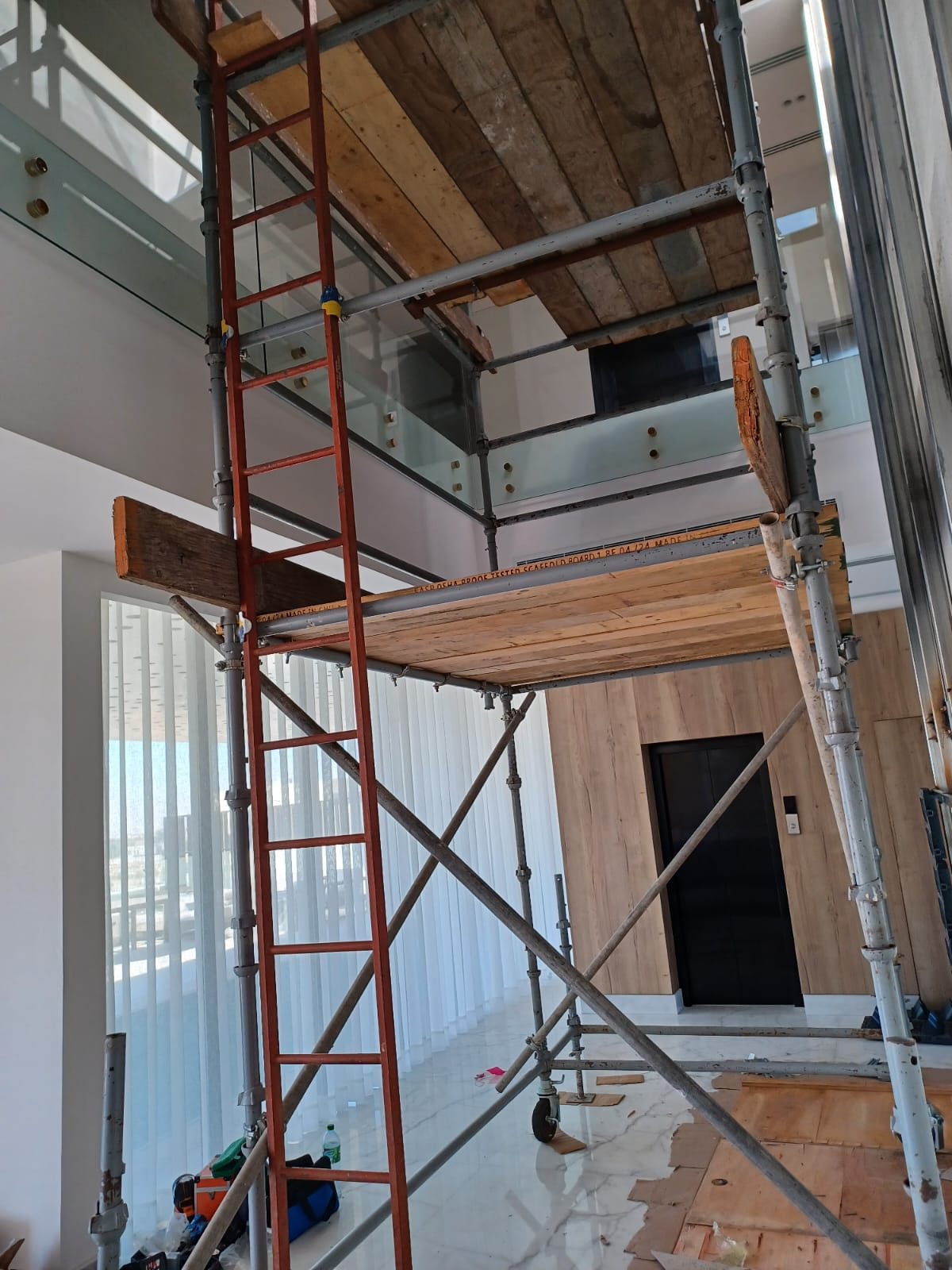Freestanding scaffold tower with two boarded levels positioned in a modern double-height interior