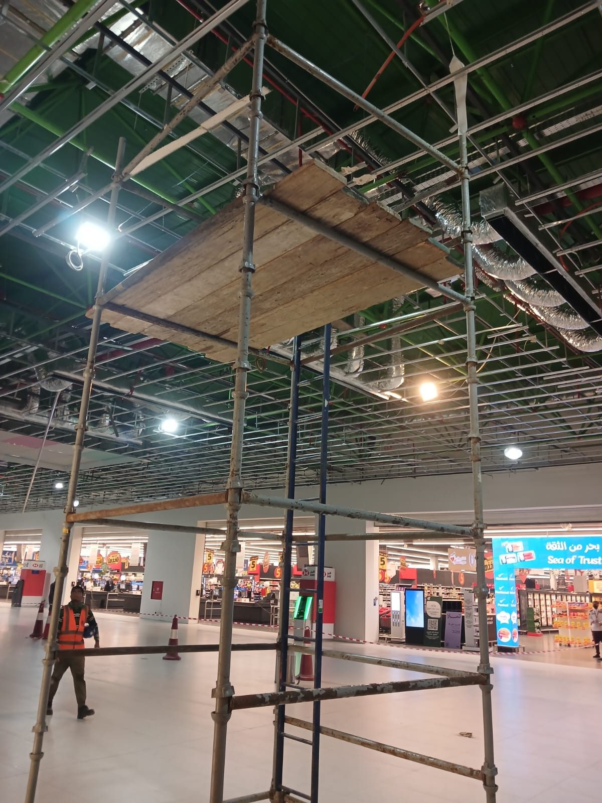 Mobile scaffolding tower inside a hypermarket for overhead services access