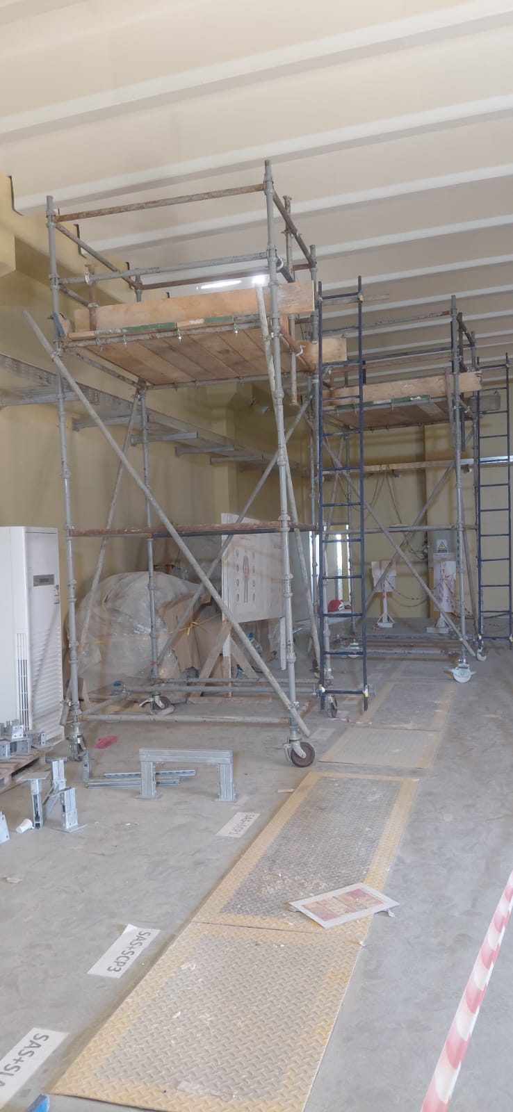 Multiple scaffolding access towers with ladders set up inside an equipment room