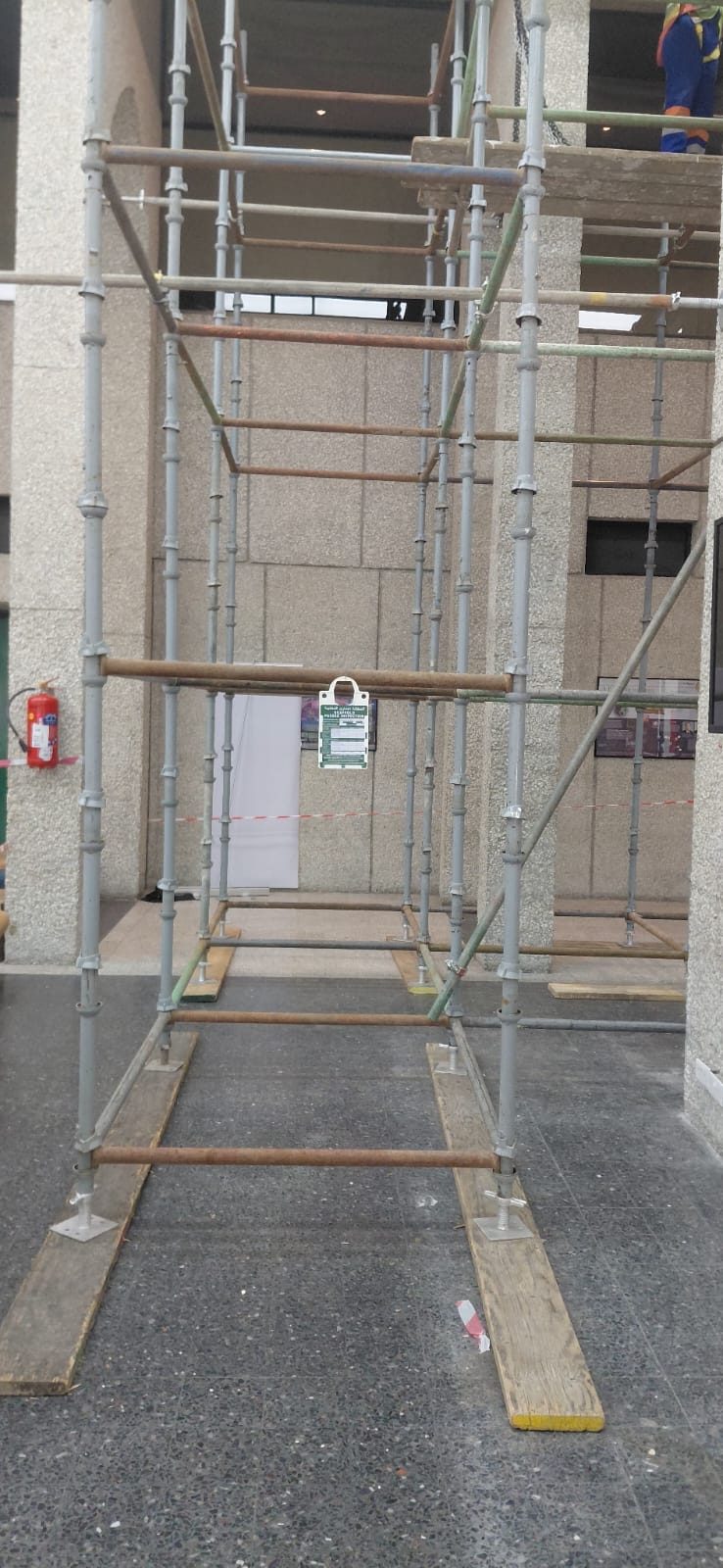 Interior scaffold tower with timber base plates erected on a polished floor against textured stone walls