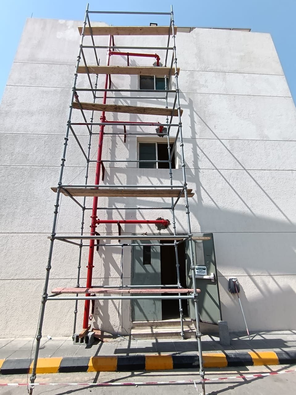 External scaffolding access towers erected against a residential building facade for fire suppression standpipe installation