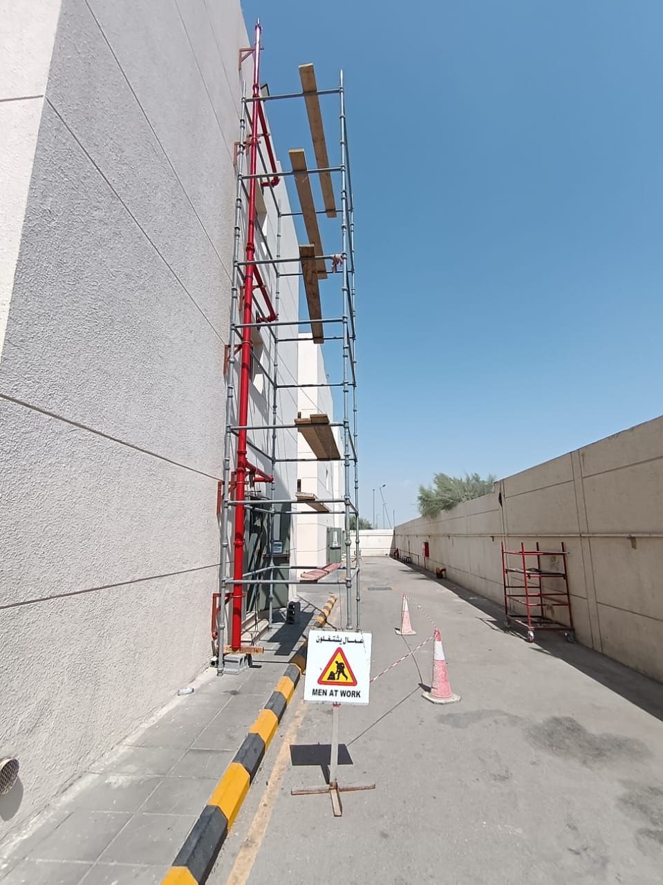 Full-height access scaffolding with timber platforms erected for exterior fire suppression pipe installation