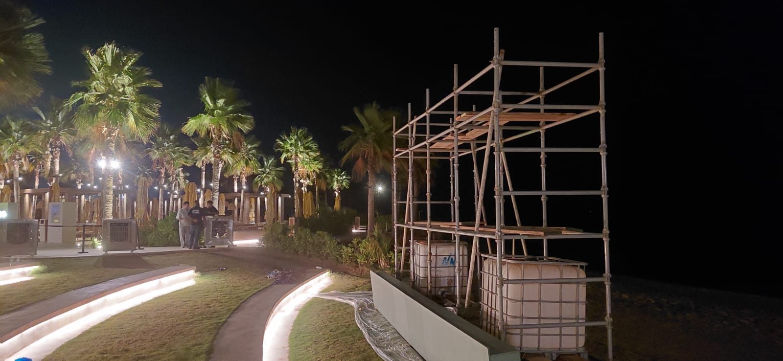 Night-time scaffolding structure near decorative landscape lighting and a resort pavilion